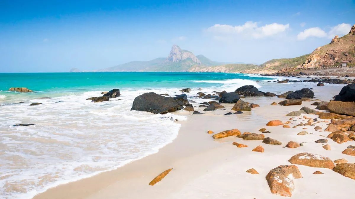 Phuoc Hai Beach's pristine white sand and crystal-clear waters nestled at the foot of verdant Minh Dam Mountain